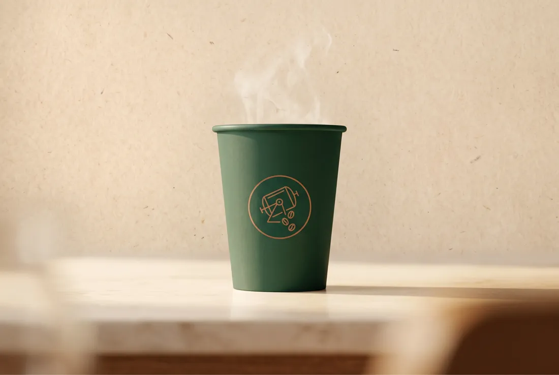A green takeaway cup with the Portsmouth Roasters mark, on a pale surface